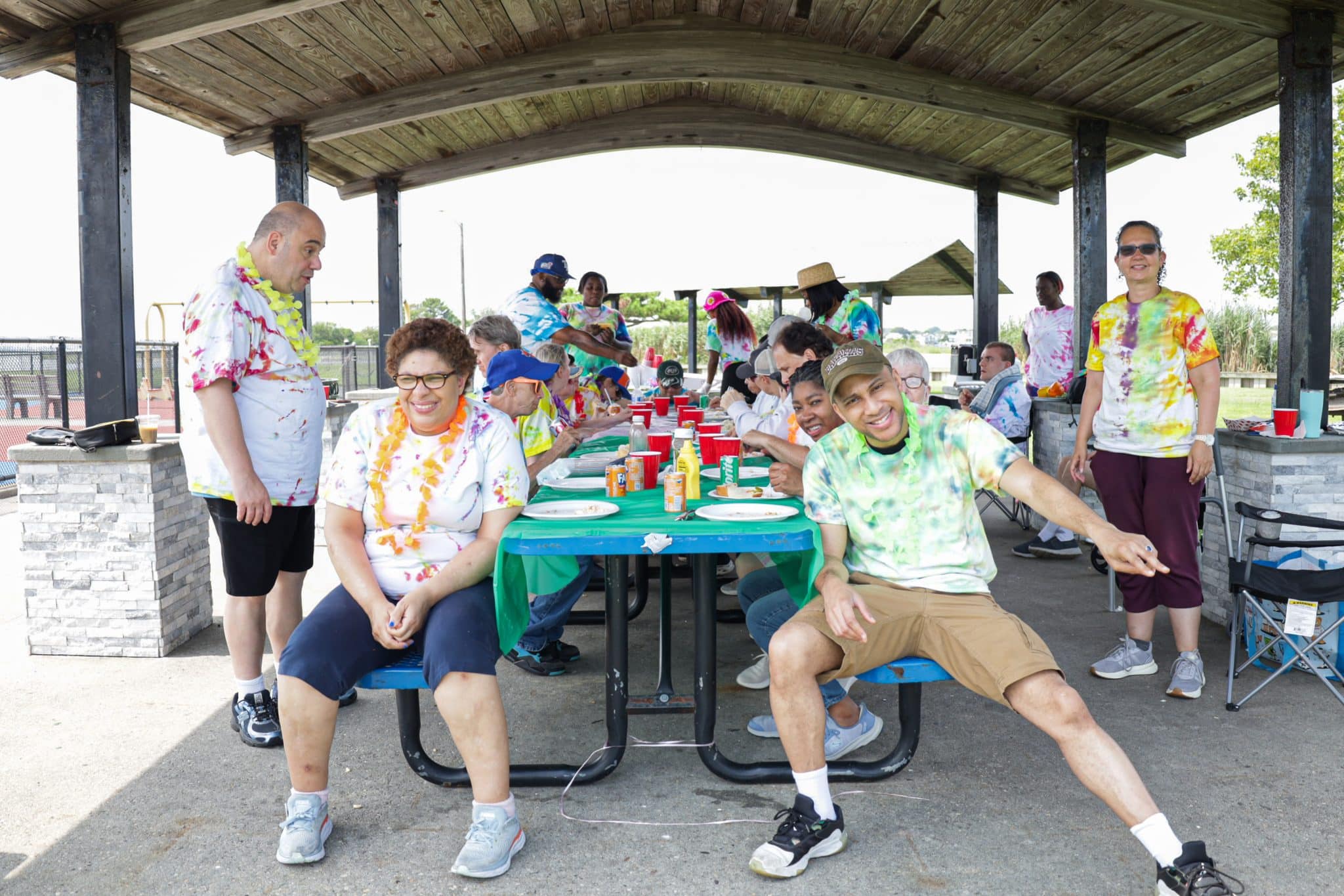 Members of Program Without Walls sit at picnic tables at their barbecue.