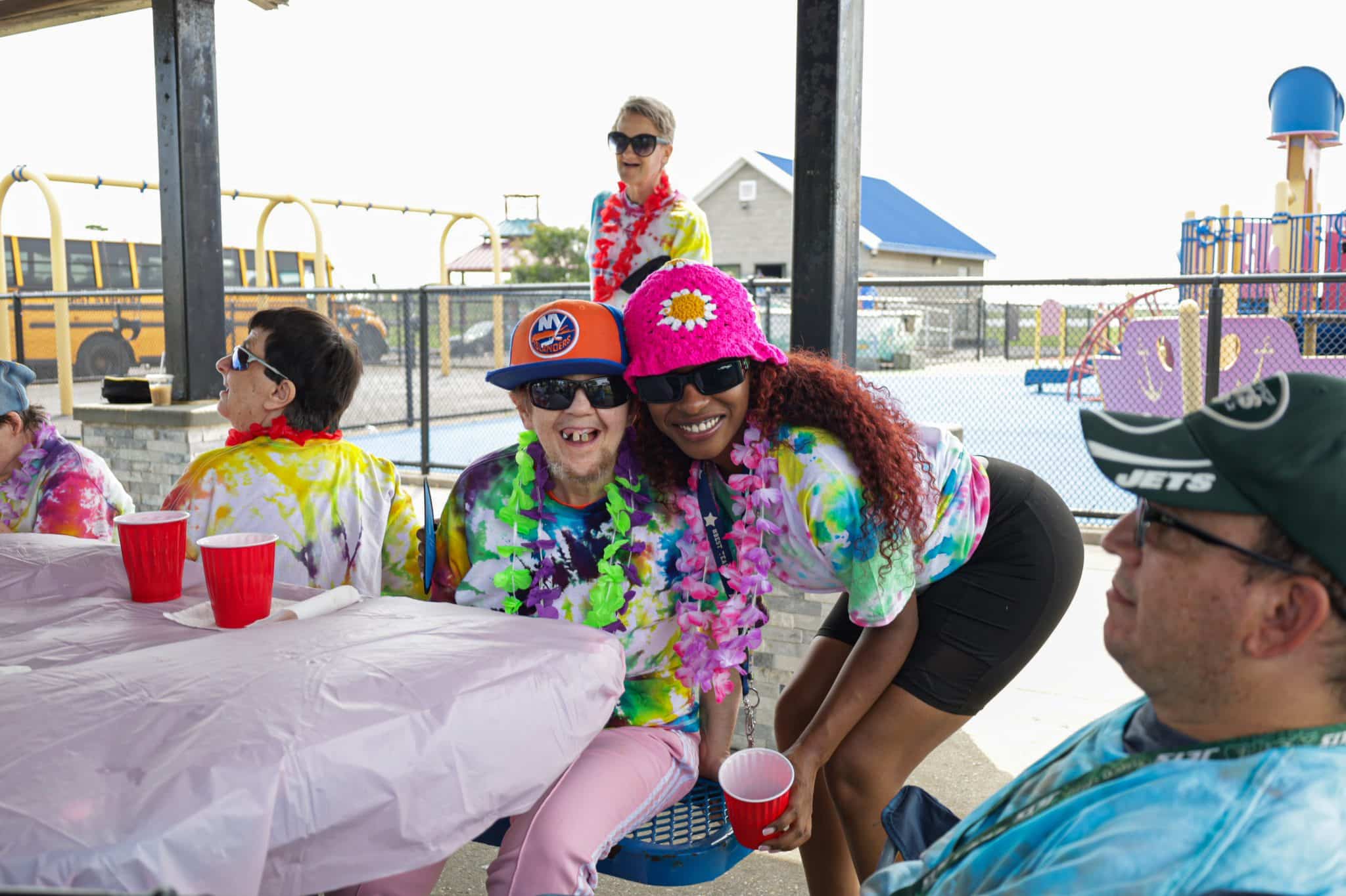A member of Program Without walls smiles alongside a staff member while wearing leis.