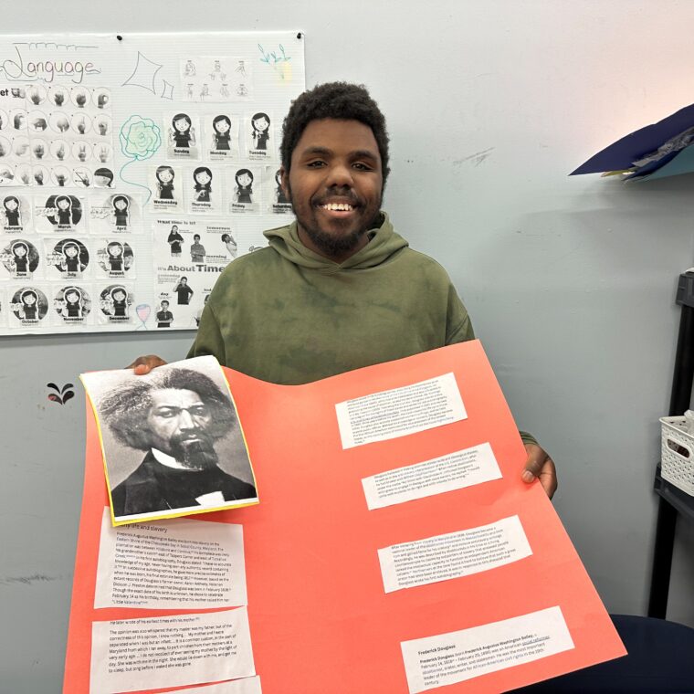 A person supported by AHRC Nassau shows off his Black History Month poster