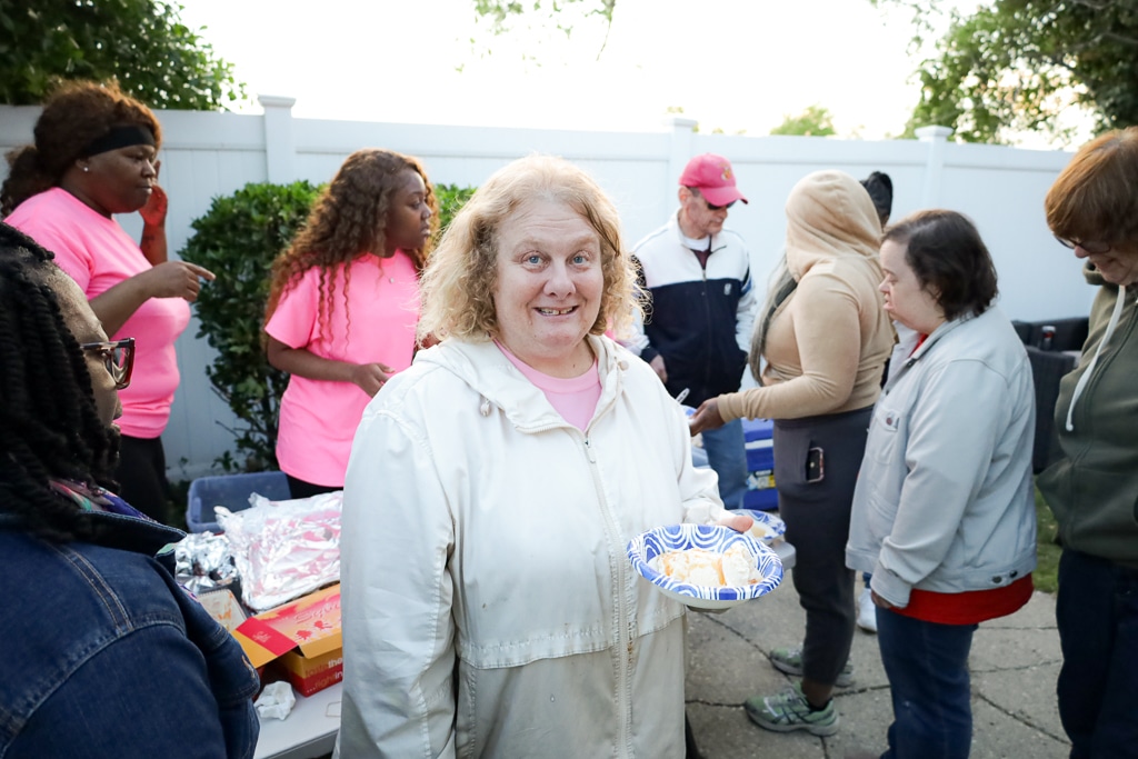 An Evers Street resident holds her food with a smile at the barbecue.
