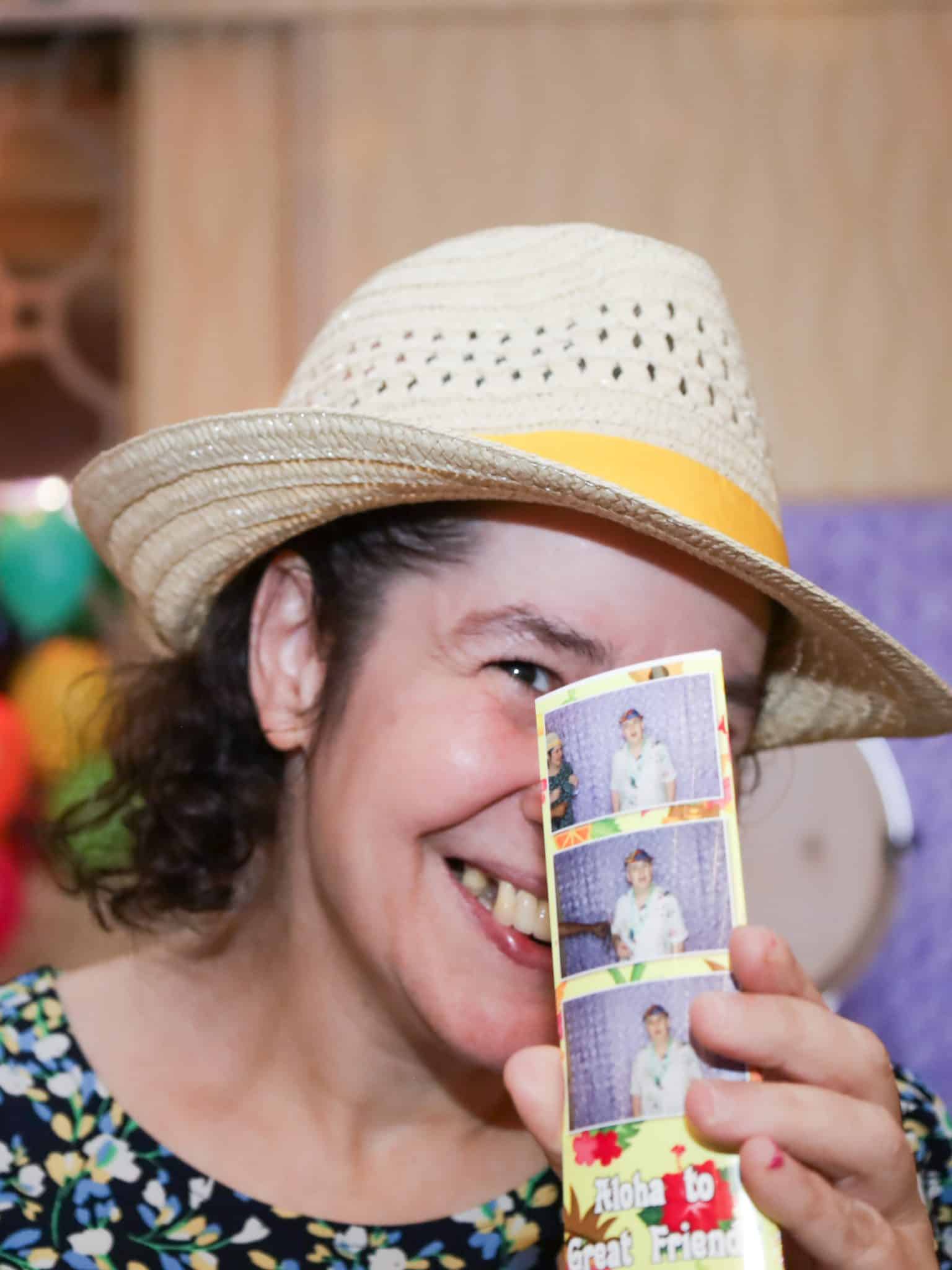 An attendee of the luau holds up a photo taken in the photobooth