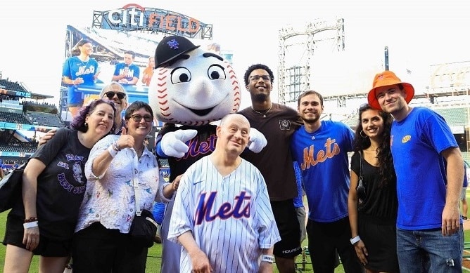 Adam Levine and his family take a photo with Mr. Met on the field at the Mets game.